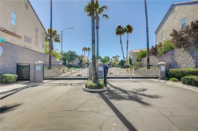 View of asphalt street featuring curbs, a gate, a gated entry, and street lights
