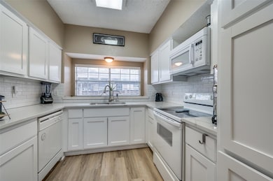 Kitchen with white cabinetry, sink, white applianc