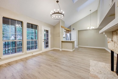 Unfurnished living room with a chandelier, light wood-type flooring, and high vaulted ceiling