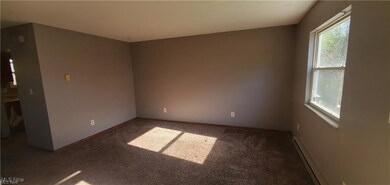 Carpeted spare room with baseboard heating and baseboards