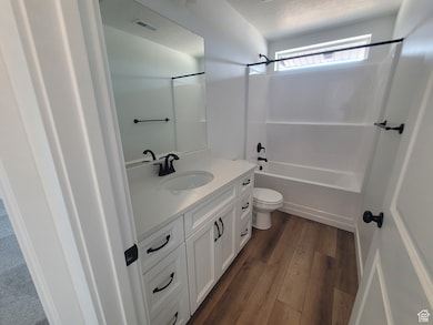 Bathroom featuring washtub / shower combination, vanity, dark wood-style flooring, and a textured ceiling