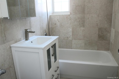 Bathroom with vanity, tile walls, and bathing tub / shower combination