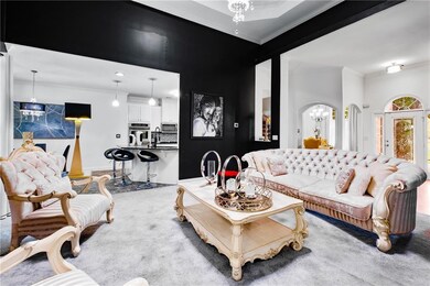Living area with a raised ceiling, a chandelier, wood finished floors, a fireplace, and crown molding