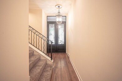 Entryway with wood finished floors, stairway, baseboards, and a chandelier