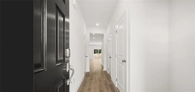 Corridor with light wood-style floors, recessed lighting, and baseboards