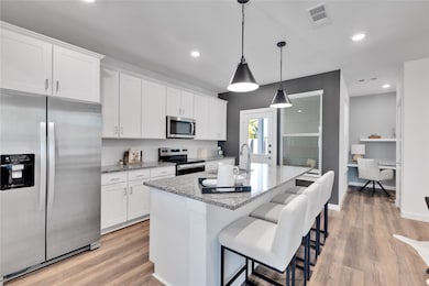 Kitchen with white cabinetry, visible vents, and appliances with stainless steel finishes