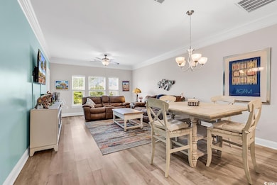 Dining area featuring ornamental molding, light wood-style floors, baseboards, ceiling fan, and a chandelier