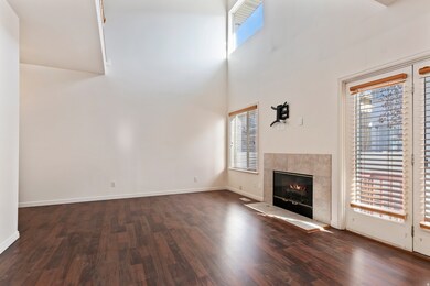 Unfurnished living room with a tiled fireplace, a high ceiling, and dark wood-style flooring