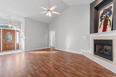 Unfurnished living room with a tile fireplace, wood finished floors, high vaulted ceiling, and ceiling fan