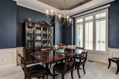 Dining space featuring a decorative wall, wainscoting, and light colored carpet