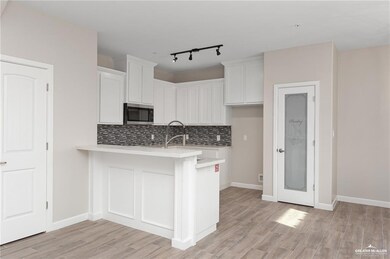 Kitchen featuring light countertops, stainless steel microwave, a peninsula, and white cabinets