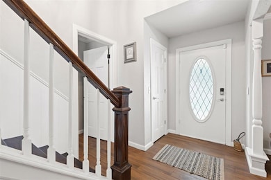 Foyer entrance featuring stairway, wood finished floors, and baseboards