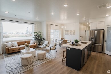 Kitchen with sink, white cabinets, hanging light fixtures, a kitchen island with sink, and stainless steel appliances