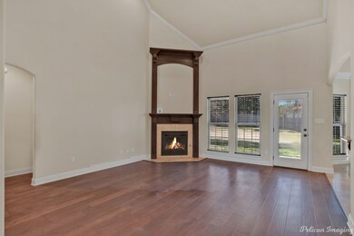 Unfurnished living room with high vaulted ceiling, ornamental molding, wood finished floors, a glass covered fireplace, and arched walkways