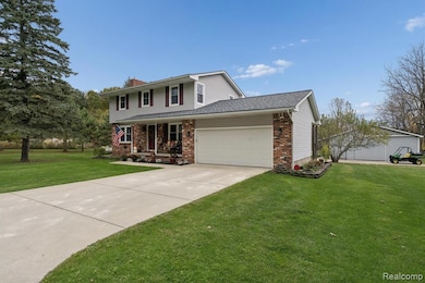 Traditional home with covered porch, a garage, a front lawn, driveway, and brick siding