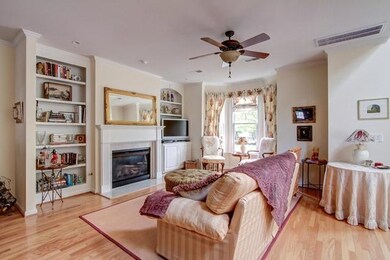 The family room has a bay window overlooking the park and custom drapes/Roman shades.  There’s a gas fireplace, flanked by built-in cabinetry & hardwood floors. 