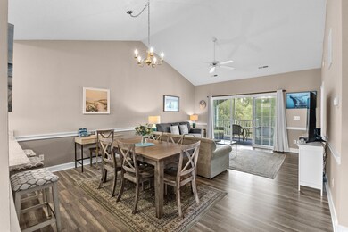 Dining space with ceiling fan, dark wood-style floors, a chandelier, and high vaulted ceiling