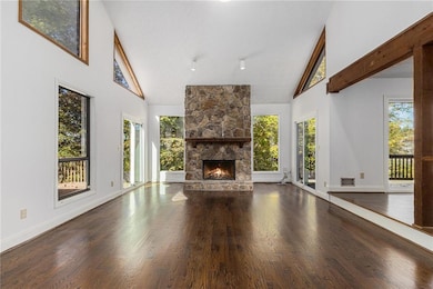 Unfurnished living room featuring high vaulted ceiling, dark wood finished floors, healthy amount of natural light, and a fireplace