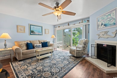 Living room featuring ceiling fan, wood finished floors, and a fireplace