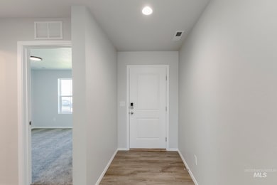 Hall with light wood finished floors and recessed lighting