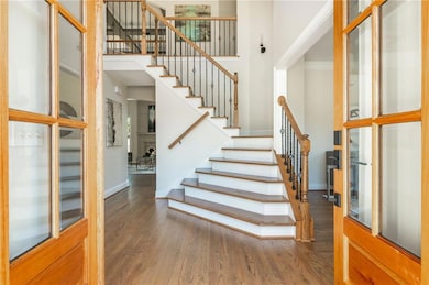 Stairway featuring baseboards, a high ceiling, and wood finished floors