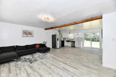 living area featuring beam ceiling, light wood-style floors, and recessed lighting