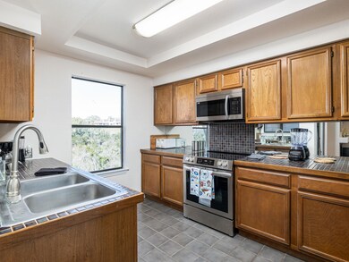 Kitchen with tile counters, brown cabinets, stain