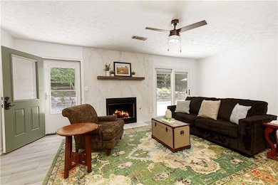 A cozy fireside moment—this textured Calcutta Blanc ceramic wall adds both character and calm, while the natural light and garden views create a sense of connection to the outdoors.
