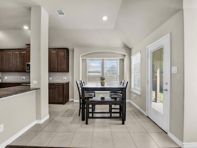 Tiled dining space featuring vaulted ceiling