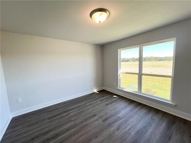 Empty room with dark wood-type flooring and baseboards