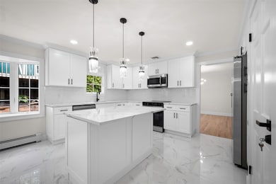 Kitchen with crown molding, tasteful backsplash, stainless steel appliances, white cabinetry, and light stone countertops