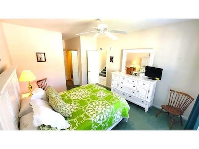 Bedroom with dark colored carpet and a ceiling fan