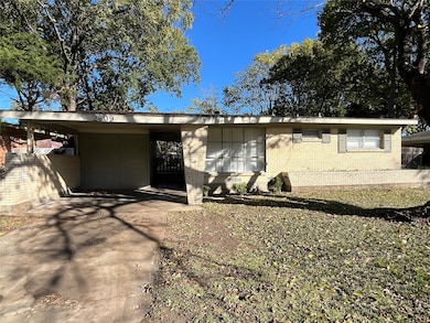 View of front facade with brick siding, a carport, and concrete driveway
