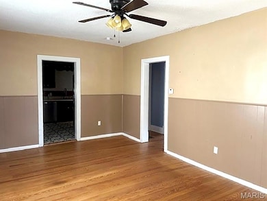 Spare room featuring a wainscoted wall, a textured ceiling, wood finished floors, and a ceiling fan