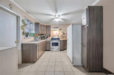 Kitchen featuring stainless steel appliances, light countertops, a ceiling fan, light tile patterned floors, and crown molding
