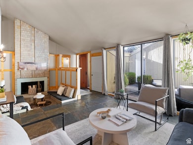 Living room with lofted ceiling, stone tile flooring, and a brick fireplace
