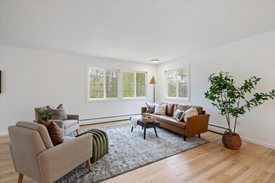 Living room with baseboard heating, wood finished floors, and baseboards