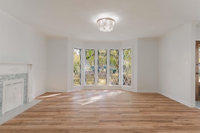 Unfurnished living room with healthy amount of natural light, light wood-style flooring, ornamental molding, and a high end fireplace