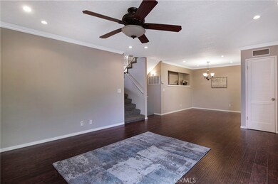Living room view to staircases to upper bedrooms and 2nd staircase to garage with laundry. Crown molding continues throughout.