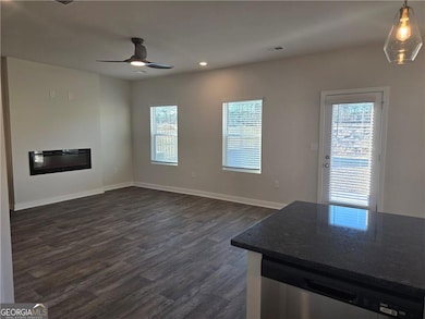 Unfurnished living room with ceiling fan, dark wood-type flooring, plenty of natural light, recessed lighting, and baseboards