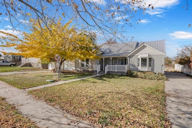 View of front facade with a porch, a metal roof, and a front yard
