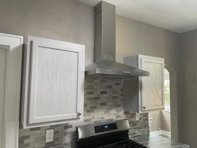 Kitchen featuring backsplash, white cabinets, wall