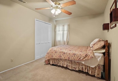 Bedroom with light carpet, ceiling fan, a closet, 