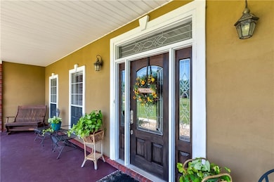 View of exterior entry featuring covered porch and stucco siding