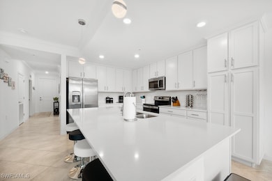 Kitchen featuring a breakfast bar area, white cabinetry, pendant lighting, appliances with stainless steel finishes, and light tile patterned flooring