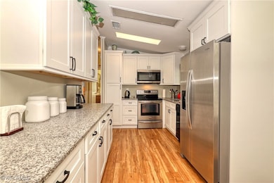 Kitchen with lofted ceiling, white cabinets, light