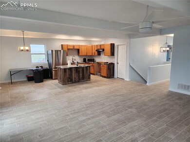 Kitchen with ceiling fan with notable chandelier, freestanding refrigerator, a center island with sink, visible vents, and tasteful backsplash