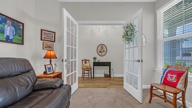 Sitting room with french doors, carpet floors, healthy amount of natural light, and baseboards