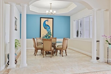 Dining room with light tile flooring, a raised ceiling, arched walkways, crown molding, and baseboards