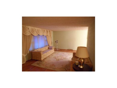 Living room is spacious and has hardwood floors.